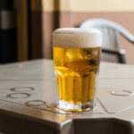 copo cheio de cerveja sobre mesa de plástico