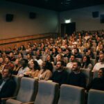 sala de cinema com público durante exibição de filme.