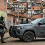 policiais de balaclava junto a viatura numa favela