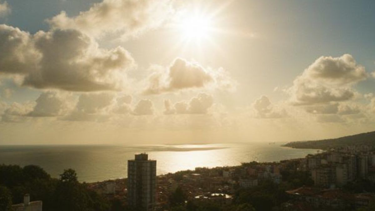 sol entre nuvens em orla urbana.
