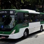ônibus saindo de ponto em frente a um parque.