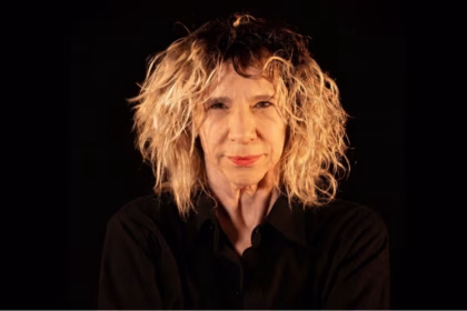 dramaturga Denise Stoklos olhando a câmera sobre fundo preto