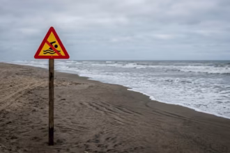 praia genérica com placa de proibição de banho.