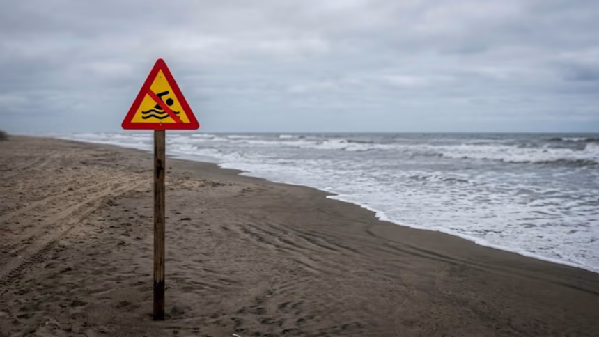 praia genérica com placa de proibição de banho.